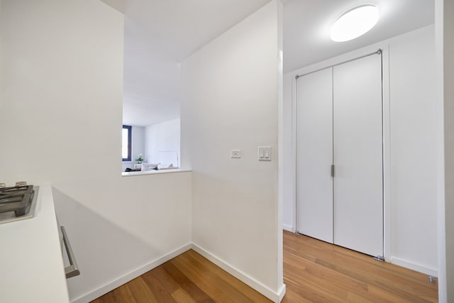 hallway featuring light wood-type flooring and baseboards