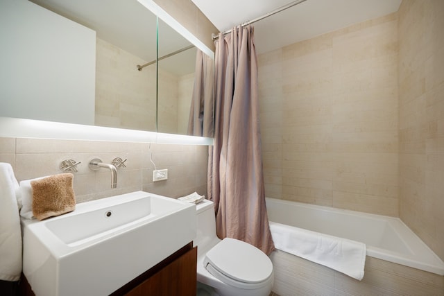 bathroom featuring toilet, tile walls, shower / bath combo with shower curtain, and vanity