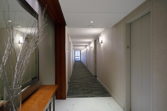 corridor featuring elevator, marble finish flooring, and recessed lighting