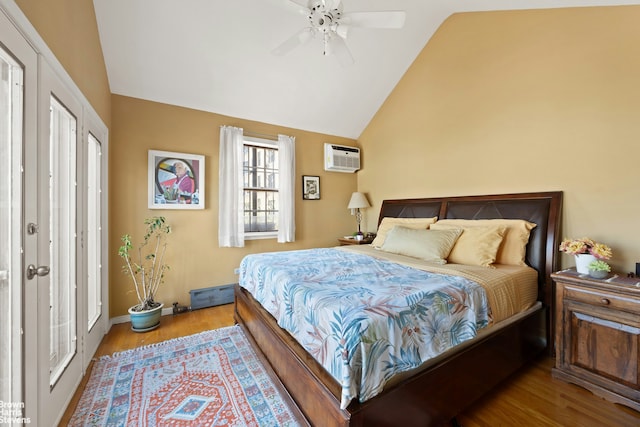 bedroom featuring lofted ceiling, wood finished floors, a wall unit AC, ceiling fan, and baseboards