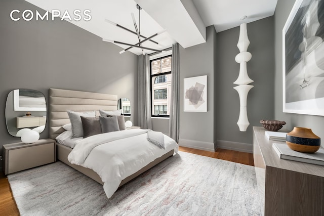 bedroom with wood finished floors, a chandelier, and baseboards