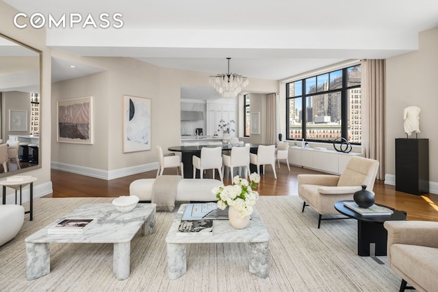 living room with baseboards, a chandelier, and wood finished floors