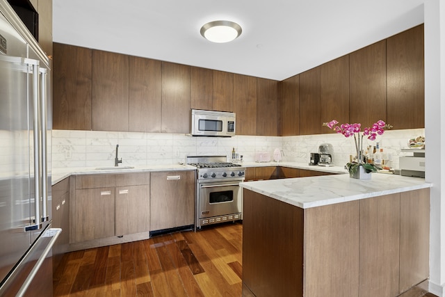 kitchen featuring high quality appliances, a sink, tasteful backsplash, dark wood-type flooring, and modern cabinets
