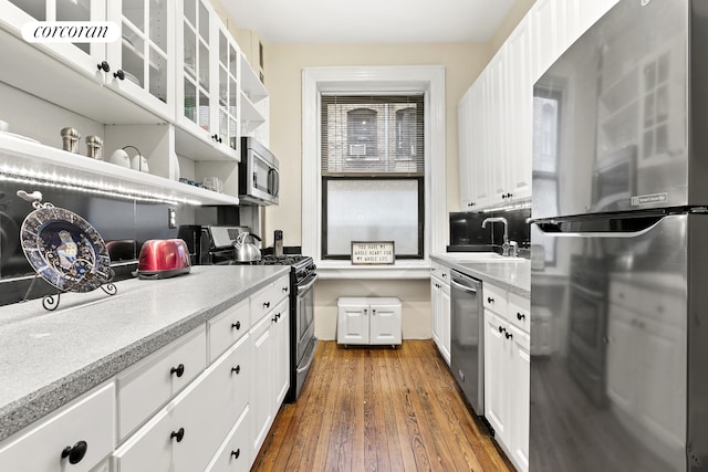 kitchen with stainless steel appliances, white cabinets, a sink, open shelves, and dark wood finished floors