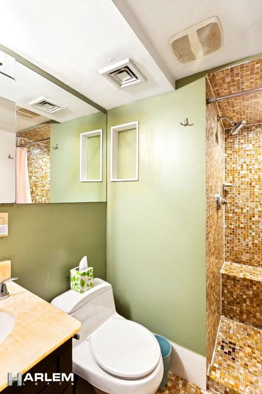 full bath featuring toilet, a tile shower, and visible vents
