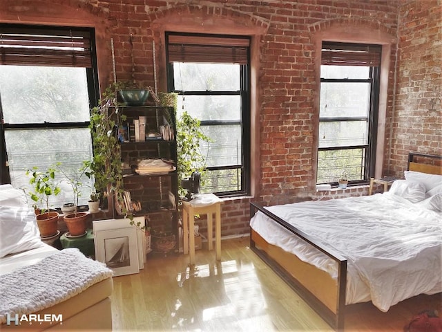 bedroom with light wood-style floors and brick wall