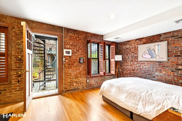 bedroom featuring multiple windows and brick wall