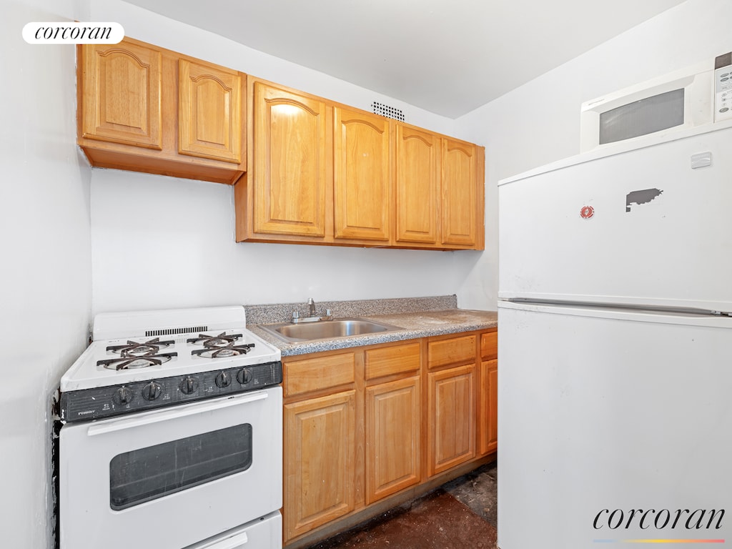 kitchen featuring a sink, white appliances, and light countertops