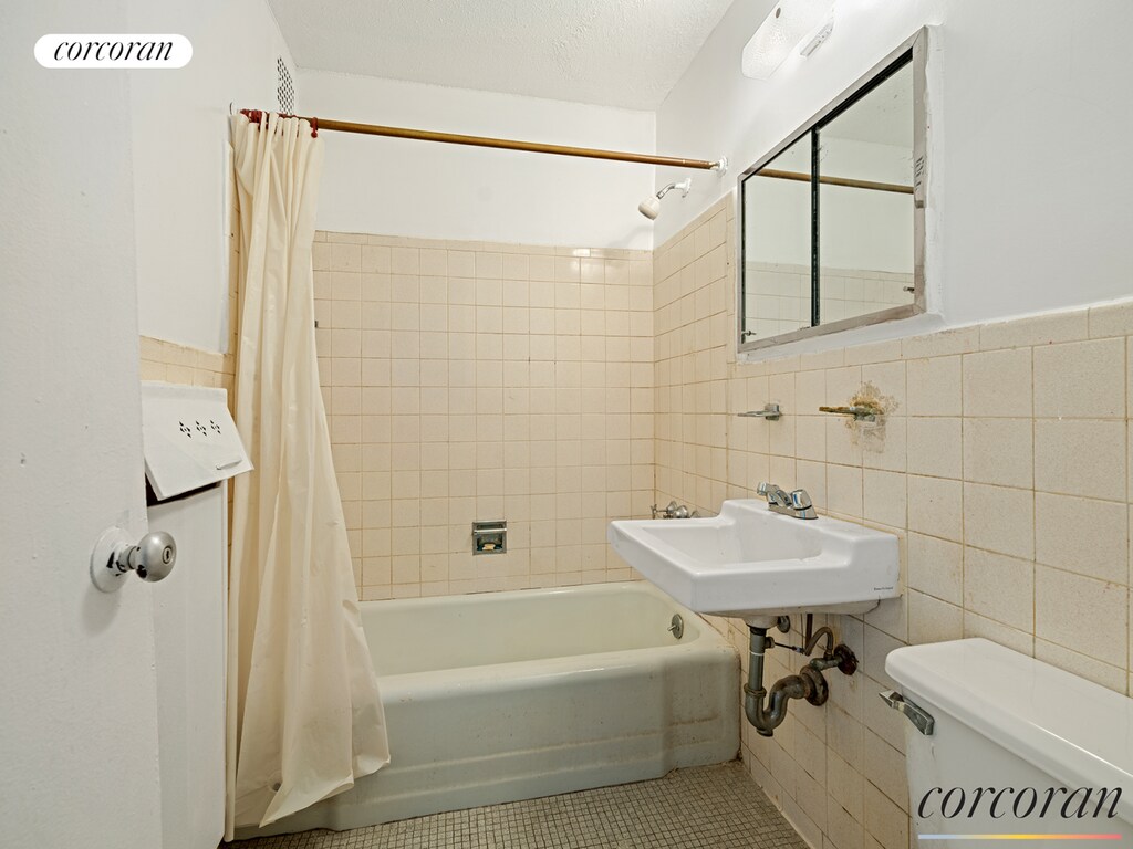 full bathroom with tile walls, tile patterned floors, toilet, and shower / bathtub combination with curtain