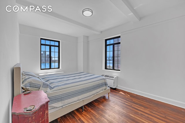 bedroom with baseboards, beamed ceiling, multiple windows, and wood finished floors