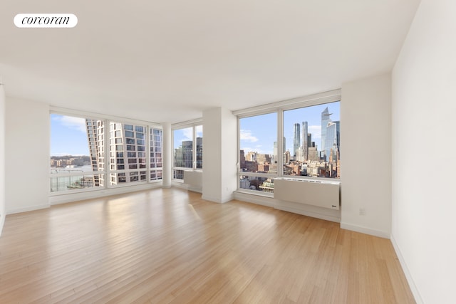 450 W 17th St Unit 2408, New York City, NY 10011 - spare room featuring a skyline view, light wood finished floors, and baseboards