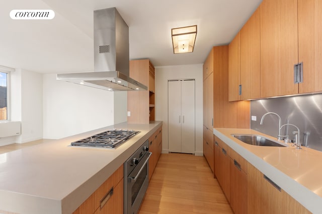 450 W 17th St Unit 2408, New York City, NY 10011 - kitchen with appliances with stainless steel finishes, island range hood, a sink, light wood-style flooring, and light countertops