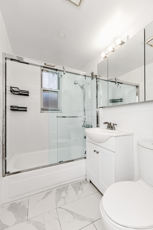 bathroom featuring toilet, combined bath / shower with glass door, marble finish floor, and vanity