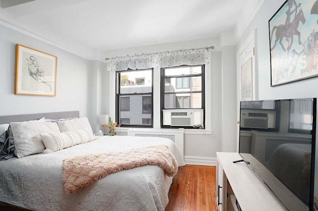 457 W 57th St Unit 911, New York City, NY 10019 - bedroom featuring radiator, wood finished floors, baseboards, and cooling unit
