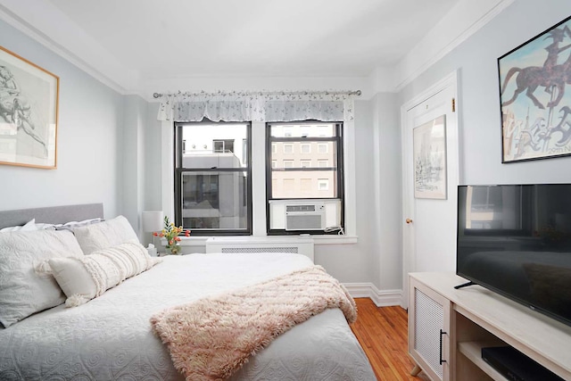 457 W 57th St Unit 911, New York City, NY 10019 - bedroom with light wood-type flooring, cooling unit, baseboards, and radiator