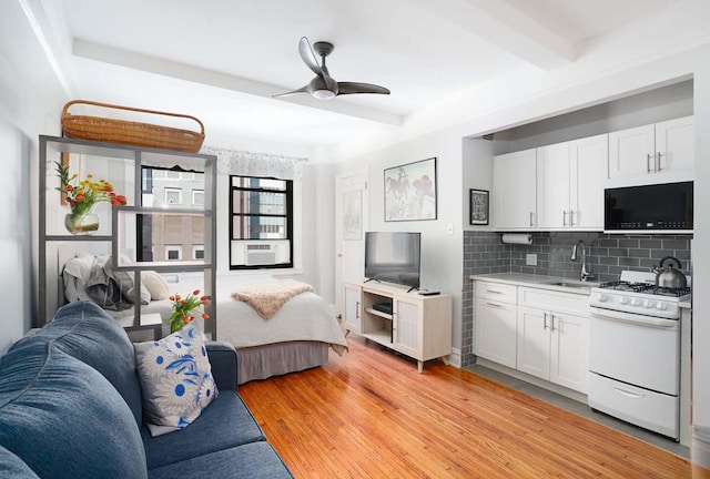 457 W 57th St Unit 911, New York City, NY 10019 - kitchen with white gas stove, black microwave, a sink, open floor plan, and light countertops