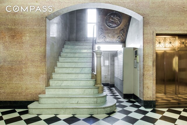 stairway with tile patterned floors and elevator