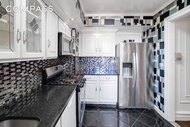 kitchen with white cabinetry, stainless steel appliances, glass insert cabinets, and backsplash