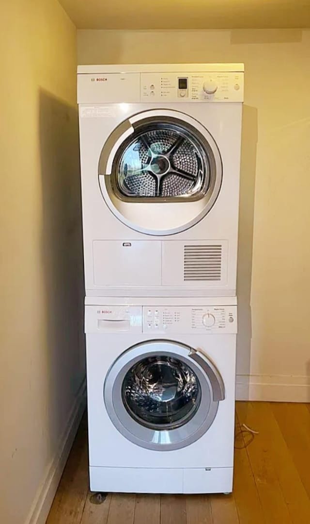 421 Hudson St Unit 305, New York City, NY 10014 - laundry area with stacked washer / dryer, baseboards, and wood finished floors