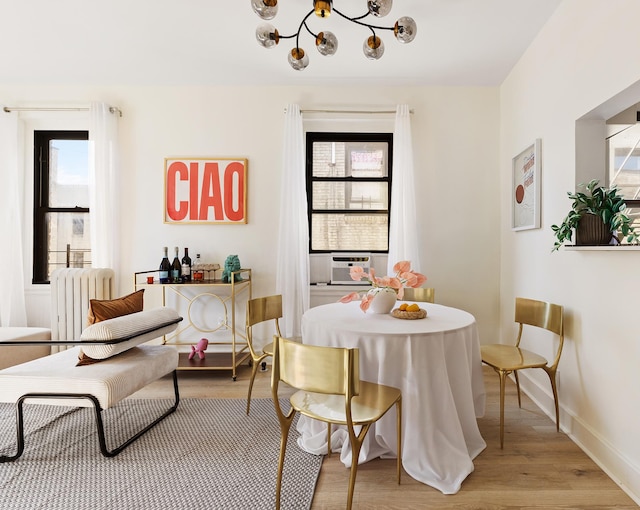 dining space featuring radiator, plenty of natural light, light wood-type flooring, and a chandelier
