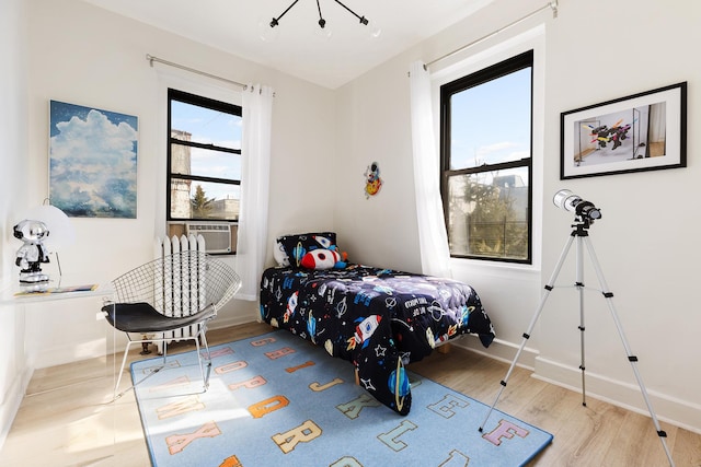 bedroom with wood finished floors, baseboards, and cooling unit