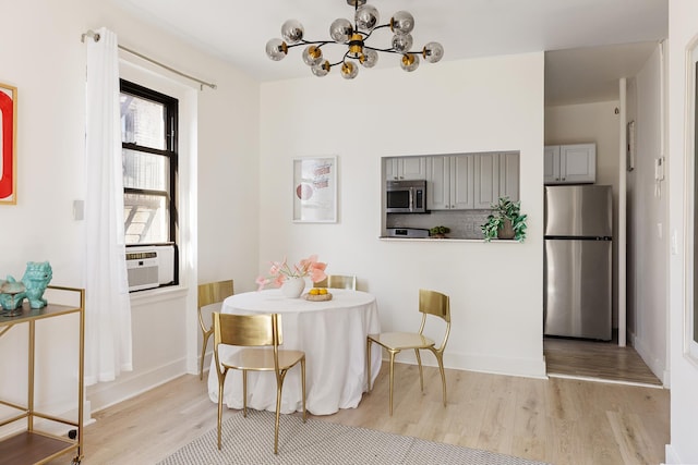 dining area featuring light wood-type flooring, a chandelier, baseboards, and cooling unit