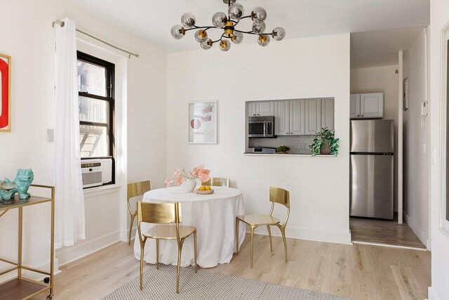 21-67 33rd St Unit 5-H, New York City, NY 11105 - dining area featuring light wood-type flooring, a chandelier, and baseboards