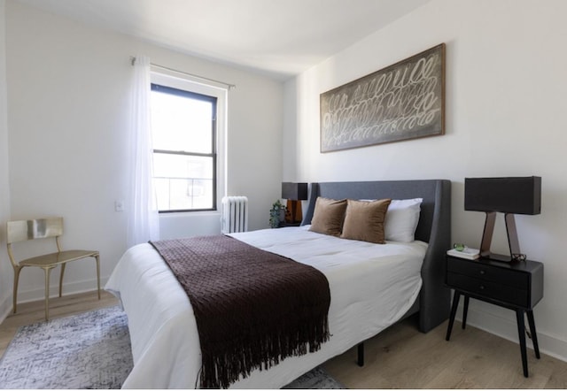 bedroom featuring radiator, wood finished floors, and baseboards