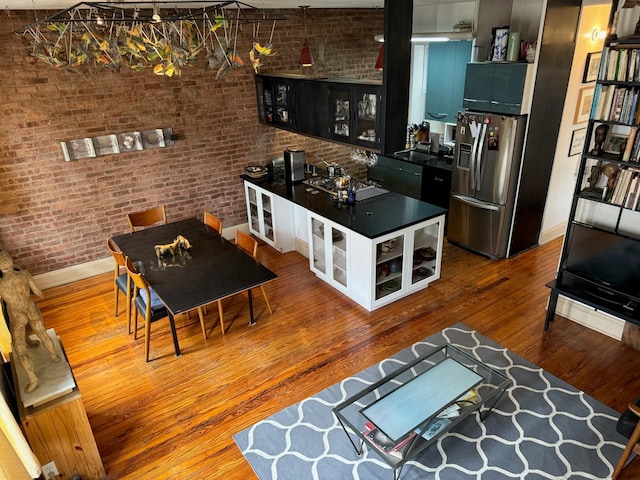 living room featuring baseboards, wood finished floors, and brick wall