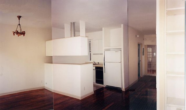 kitchen featuring pendant lighting, dark wood-style floors, freestanding refrigerator, dishwasher, and a peninsula