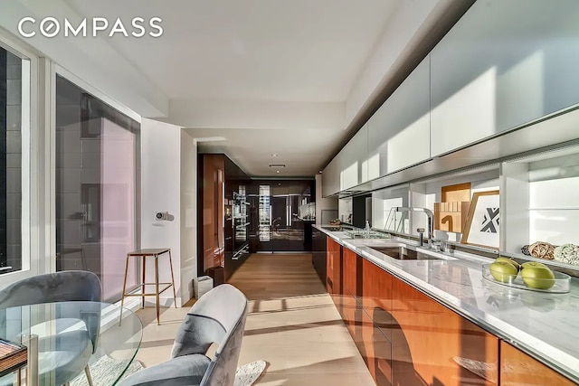 135 W 52nd St Unit 40A, New York City, NY 10019 - kitchen featuring modern cabinets, light stone counters, brown cabinetry, and white cabinetry