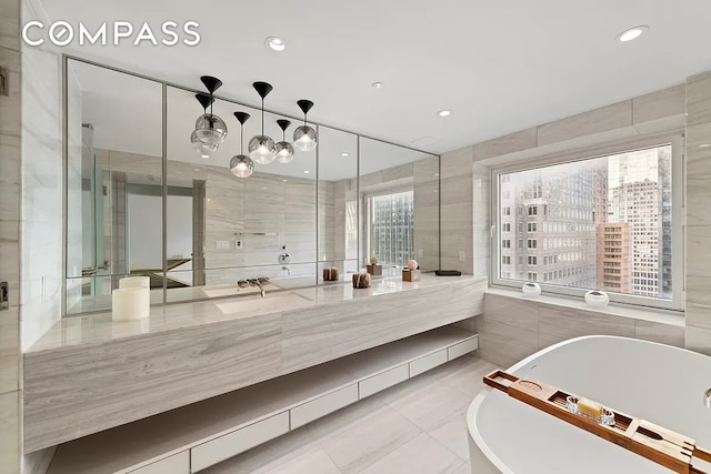 135 W 52nd St Unit 40A, New York City, NY 10019 - full bathroom with tile walls, vanity, a freestanding tub, tile patterned floors, and recessed lighting