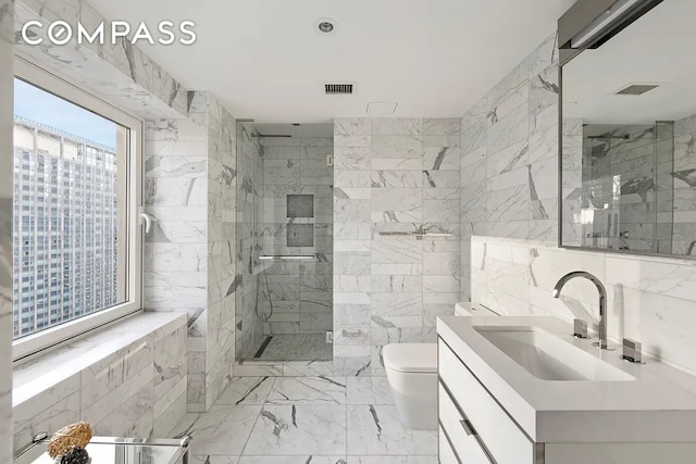 135 W 52nd St Unit 40A, New York City, NY 10019 - bathroom featuring vanity, tile walls, a marble finish shower, and marble finish flooring
