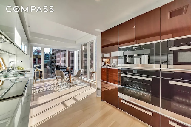 135 W 52nd St Unit 40A, New York City, NY 10019 - kitchen featuring light wood-style flooring, modern cabinets, and light countertops
