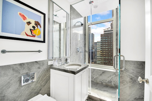 bathroom with tile walls, a shower stall, a view of city, and vanity