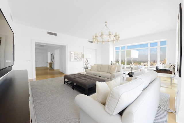 living room featuring visible vents, wood finished floors, and an inviting chandelier