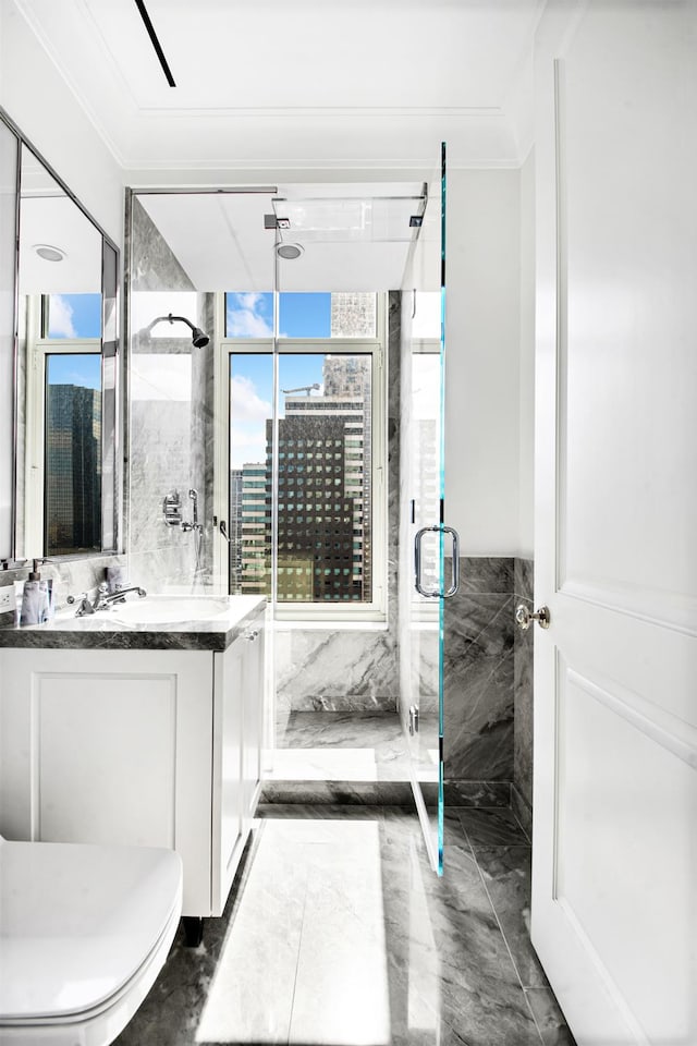 full bathroom with a shower stall, marble finish floor, tile walls, vanity, and crown molding