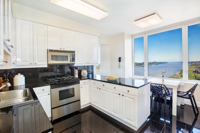 kitchen with a peninsula, dark countertops, appliances with stainless steel finishes, and a sink