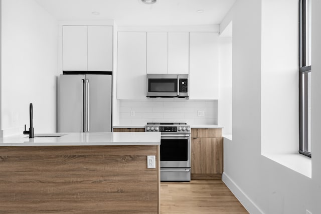 kitchen featuring a sink, modern cabinets, white cabinets, and stainless steel appliances