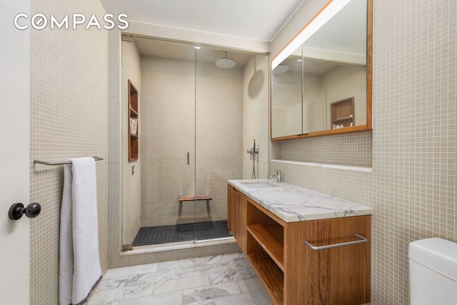 full bathroom featuring marble look tiles, a shower stall, vanity, toilet, and tile walls