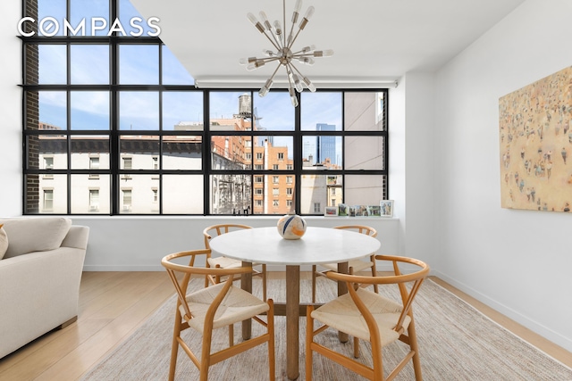 dining area featuring a chandelier, wood finished floors, baseboards, and a view of city