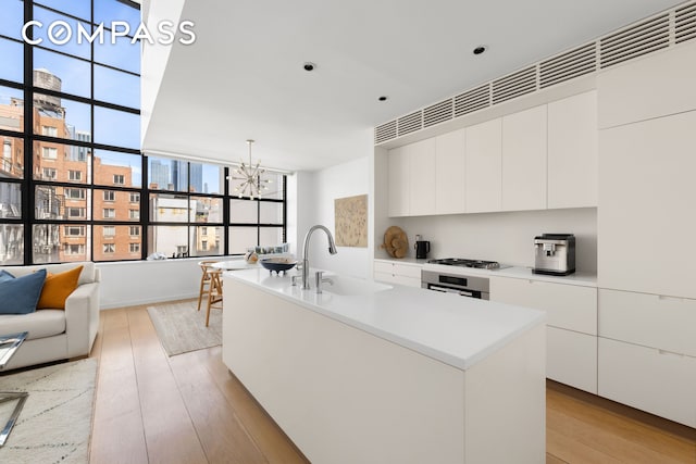 kitchen featuring a sink, modern cabinets, a chandelier, and white cabinetry