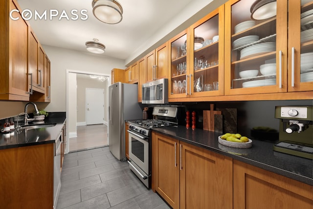kitchen with stainless steel appliances, a sink, brown cabinets, and tile patterned floors