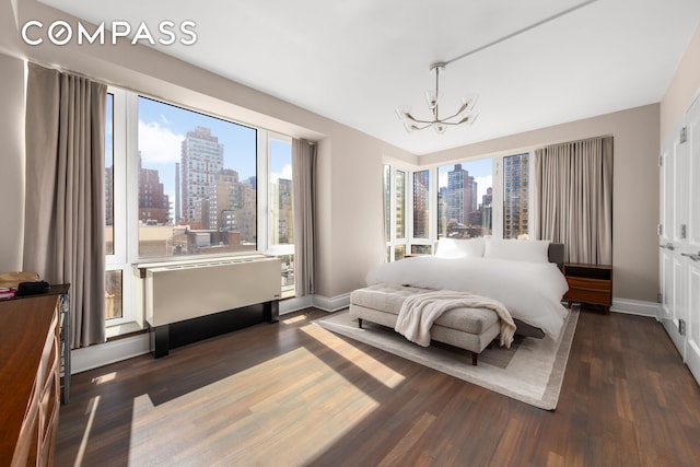 bedroom with a view of skyline, a chandelier, wood finished floors, and baseboards