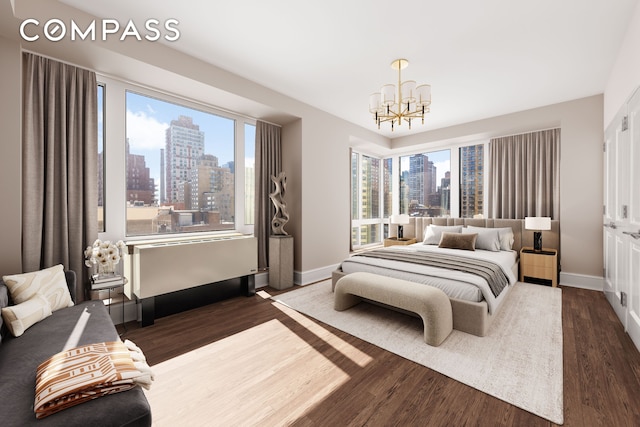 bedroom featuring a view of skyline, a chandelier, baseboards, and dark wood finished floors