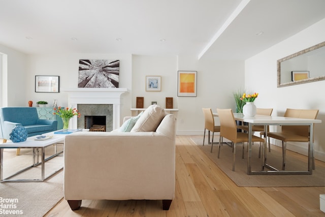 living area featuring baseboards, recessed lighting, light wood-style flooring, and a premium fireplace