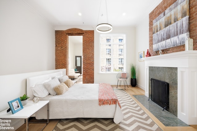 bedroom featuring a fireplace with flush hearth, ornamental molding, recessed lighting, and wood finished floors