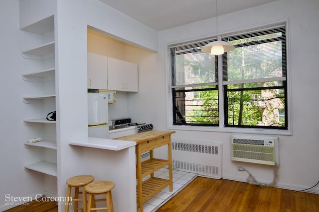 kitchen featuring hanging light fixtures, freestanding refrigerator, a breakfast bar, open shelves, and radiator