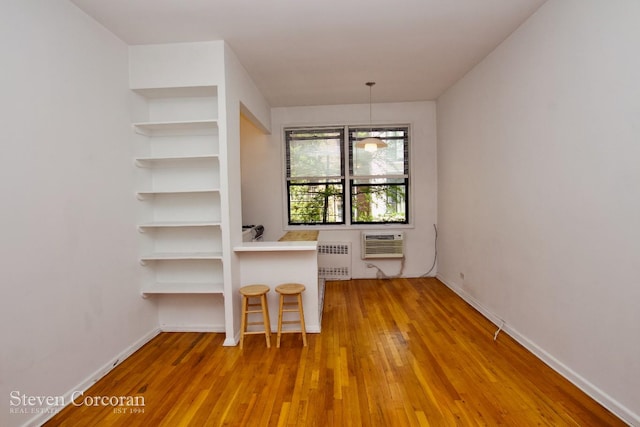 148 E 84th St Unit 2A, New York City, NY 10028 - unfurnished dining area with radiator, wood finished floors, an AC wall unit, and baseboards