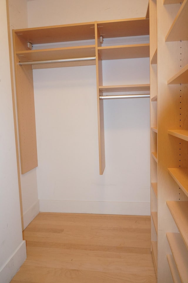walk in closet with wood finished floors